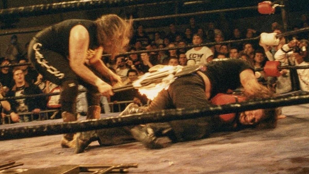 Mick Foley hitting Tommy Dreamer, who is lay across Terry Funk, with a flaming chair