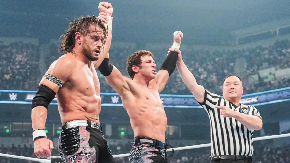 Motor City Machine Guns celebrate victory in the ring with raised hands as the referee signals the win.