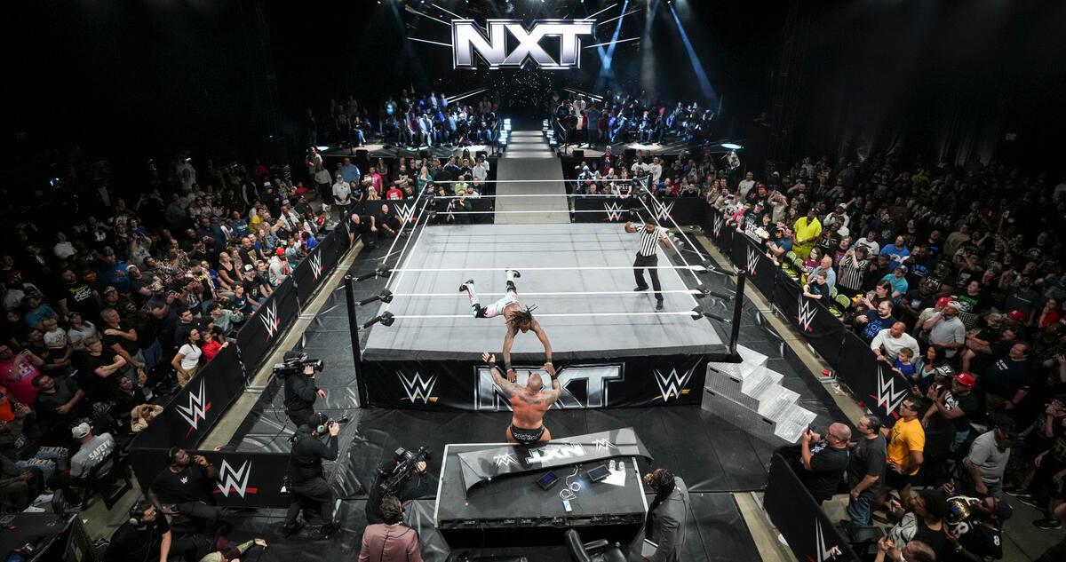 NXT set in October 2024 with Je'Von Evans hitting a suicide dive to Randy Orton