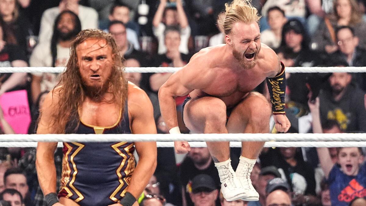 Pete Dunne looking stoic as Tyler Bate jumps in the air