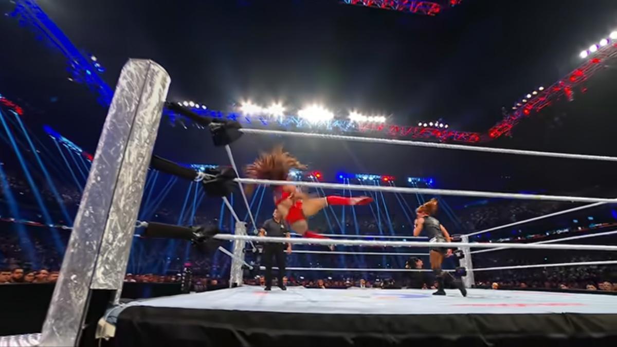 Nikki Bella falling to the ring after missing a kick as Becky Lynch stands away from her