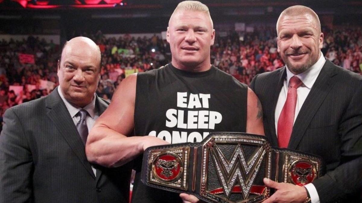Brock Lesnar holding the WWE Title with Paul Heyman to his left and Triple H to his right