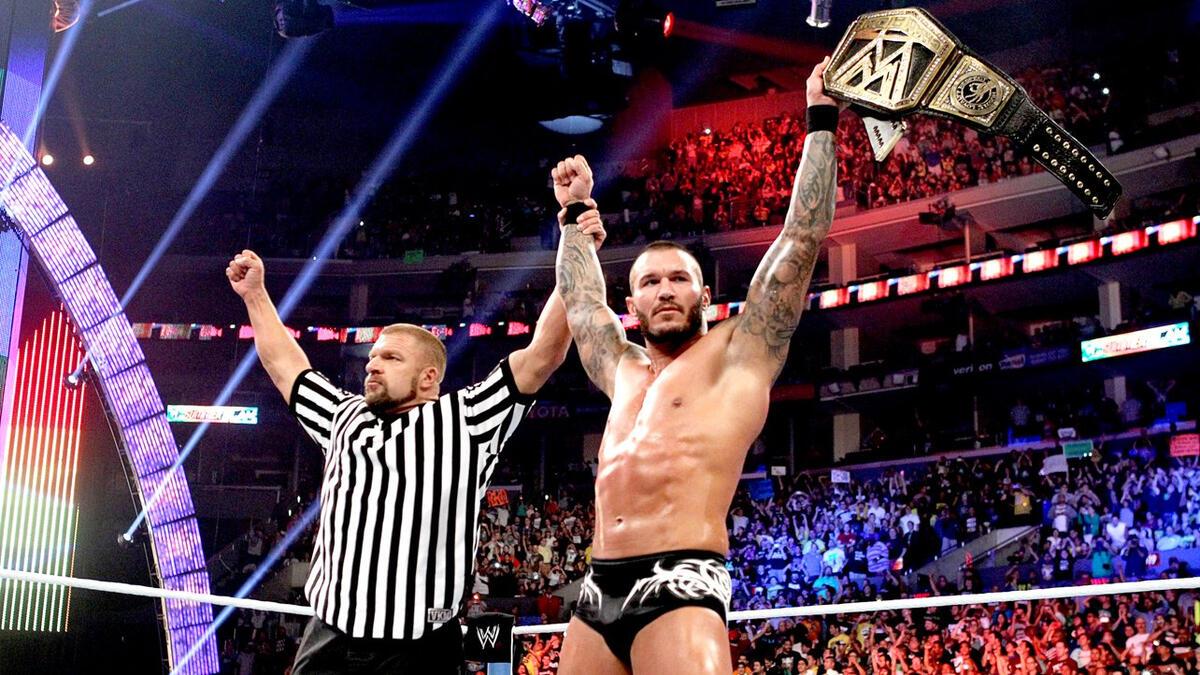 Triple H raising Randy Orton, who is holding the WWE Title, at SummerSlam 2013