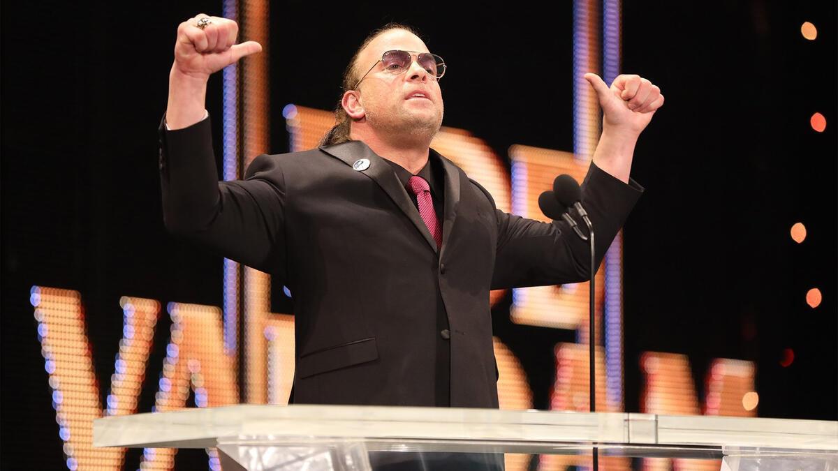 Rob Van Dam in suit and sunglasses doing his signature thumbs pose on stage at the WWE Hall of Fame ceremony