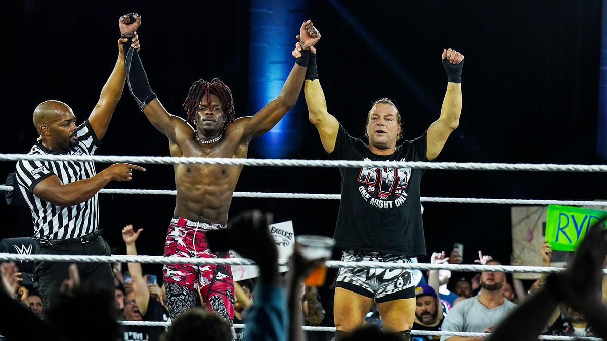 Je'Von Evans and Rob Van Dam with raised arms in the ring, celebrating victory, with a referee pointing at them.