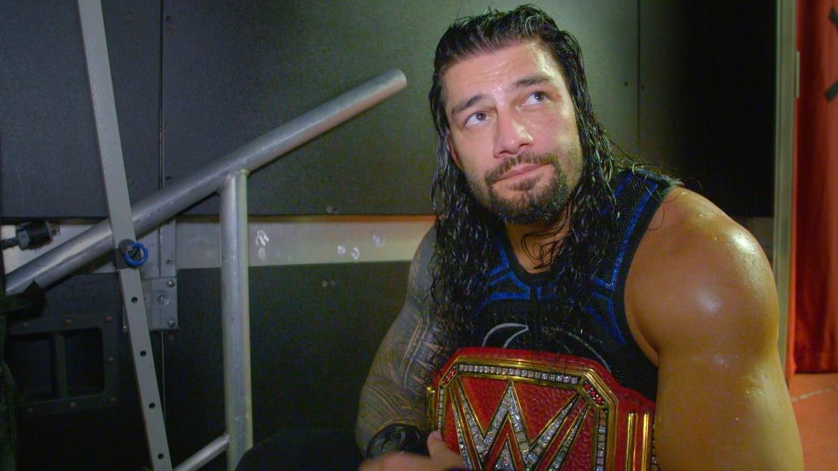 Roman Reigns holding the Universal Title while sitting on a production case at WWE SummerSlam 2018