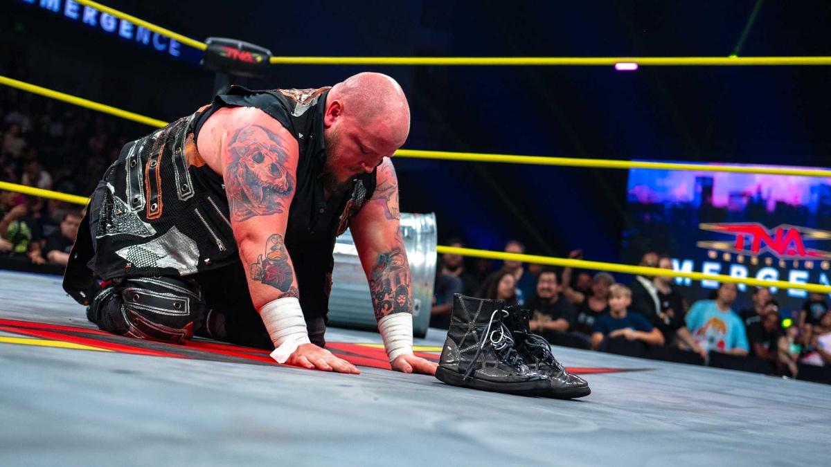Sami Callihan kneeling down in the ring with his boots in front of him