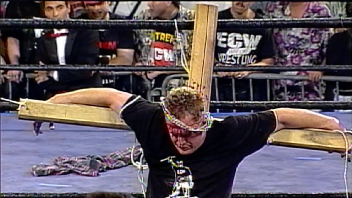 The Sandman strapped to a cross with barbed wire on his head at ECW High Incident