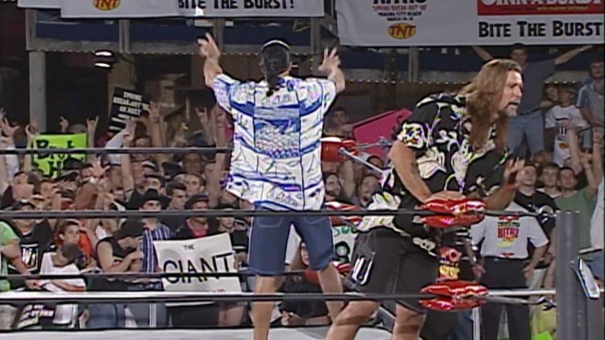 Kevin Nash leaning over the ropes as Scott Hall dances for the crowd behind him 