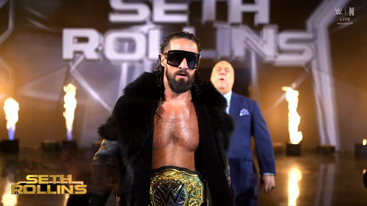 Seth Rollins wearing a black coat, sunglasses and the World Heavyweight Title around his waist