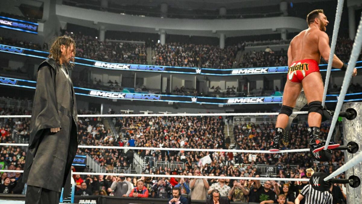 Shinsuke Nakamura standing behind LA Knight, who is on the ropes looking at a wrestling crowd