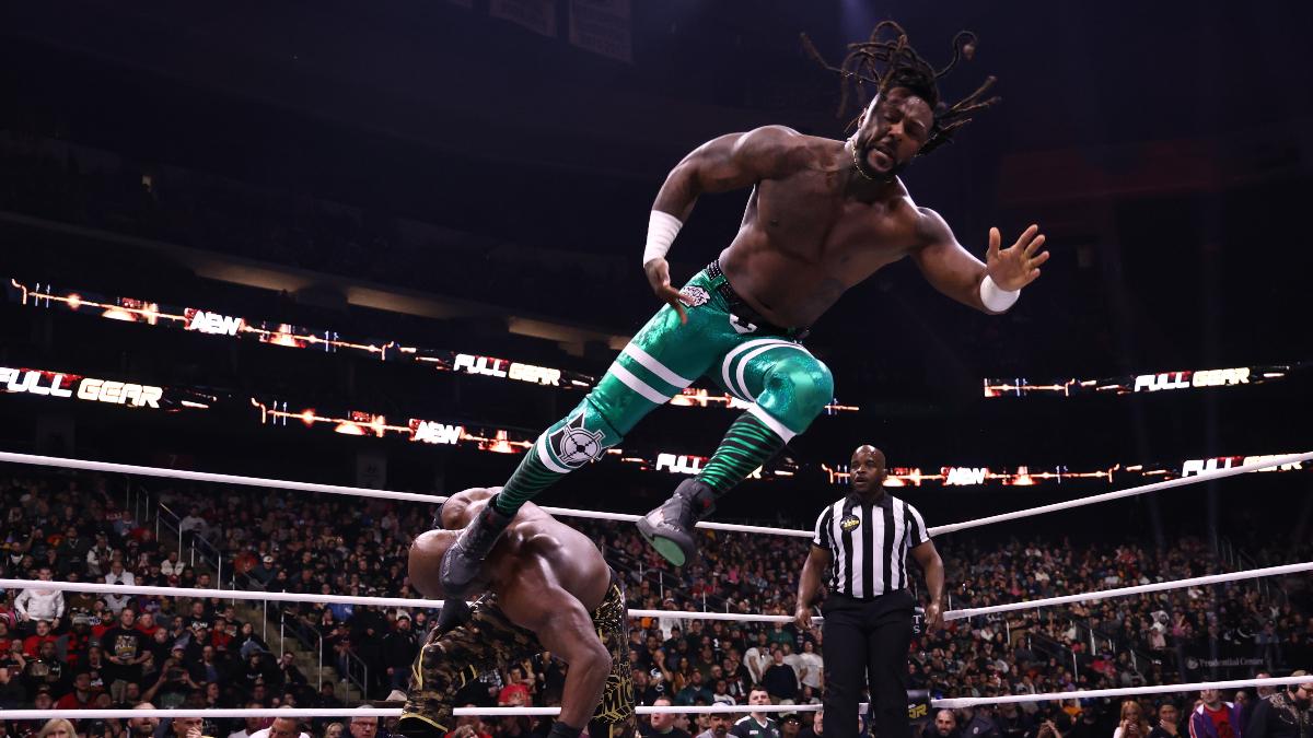 Swerve Strickland hitting a flying House Call kick to Bobby Lashley's head in an AEW wrestling ring as the ref watches on