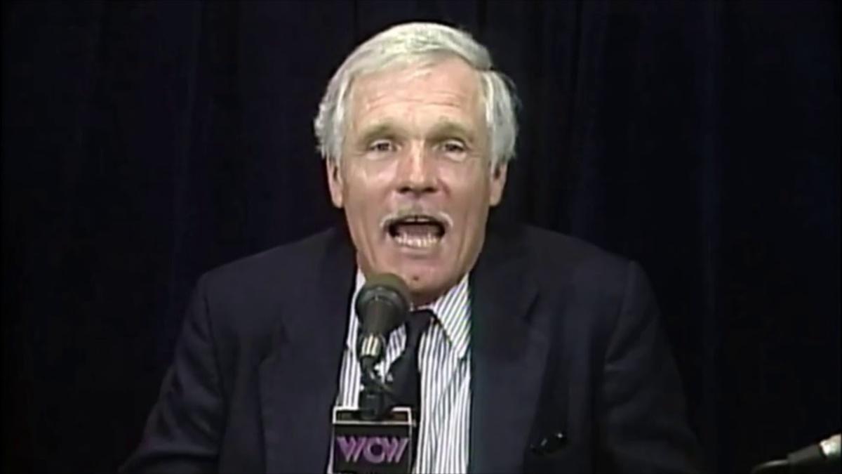 Ted Turner in suit with microphone, dark background, "WCW" logo visible on mic flag.