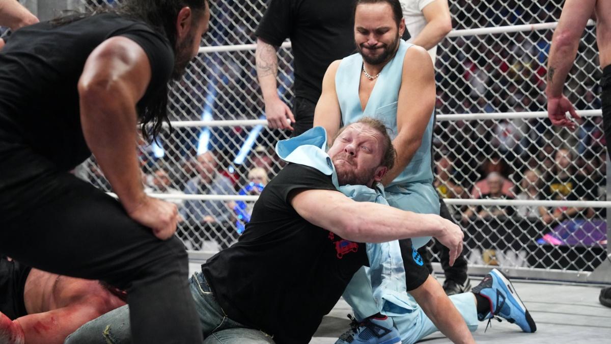 The Young Bucks choking out Kenny Omega with a suit jacket inside a steel cage 