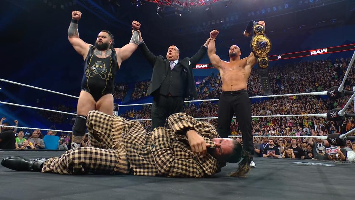 Paul Heyman raising Bronson Reed and Bron Breakker's arms as they stand over Seth Rollins