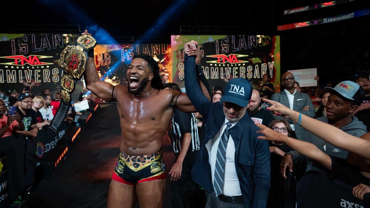 Trick Williams holding the TNA World Title and having his arm raised by TNA President Carlos Silva