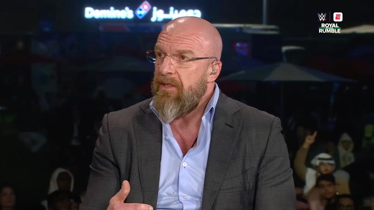 Triple H sitting down in a grey suit wearing glasses