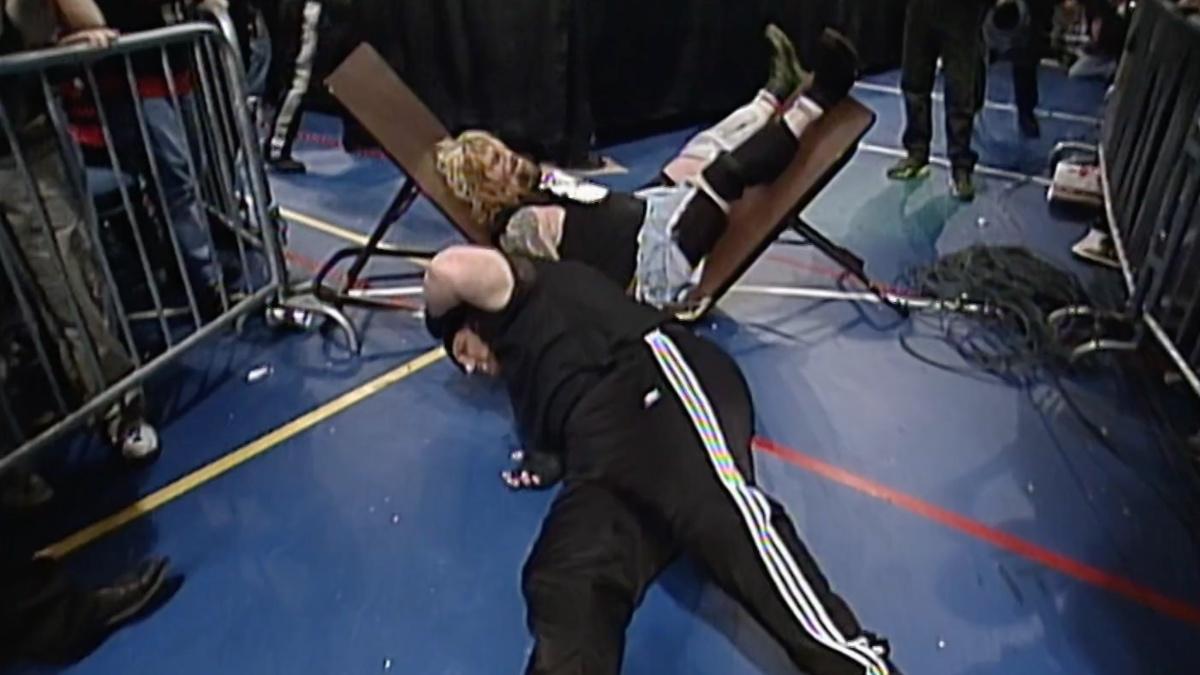 Vic Grimes lay down in pain as Balls Mahoney is behind him in the middle of a broken table 