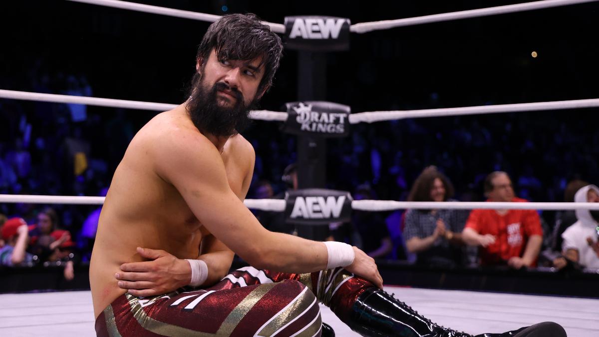 Wheeler Yuta sitting in a ring with AEW branding on the ropes, with an audience in the background.