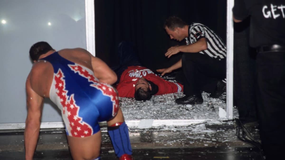 Kurt Angle lay in glass with Kurt Angle beginning to get to his feet as referee Mike Chioda checks on Shane at WWE King of the Ring 2001