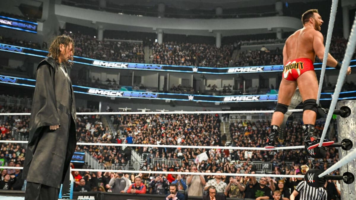 Shinsuke Nakamura standing behind LA Knight, who is on the ropes looking at a wrestling crowd