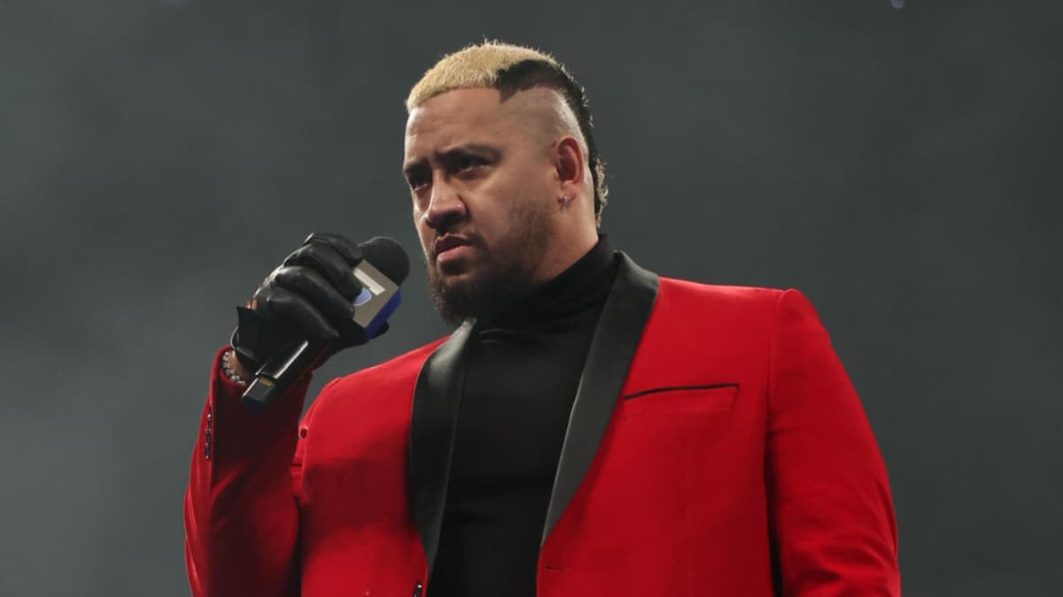 Solo Sikoa holding a microphone in a red suit