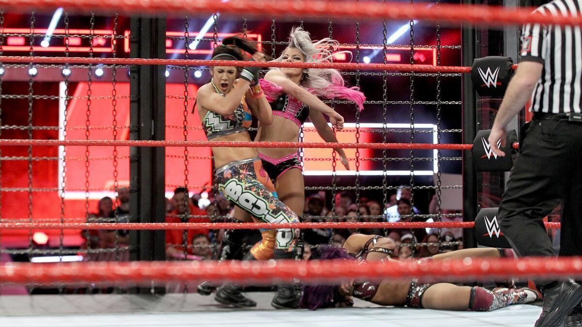 Alexa Bliss slapping Bayley as Sasha Banks lies next to them at WWE Elimination Chamber 2018